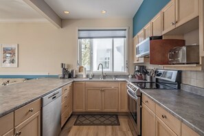 Kitchen features a stainless steel dishwasher, oven, microwave, and toaster, with ample natural light from the window.
