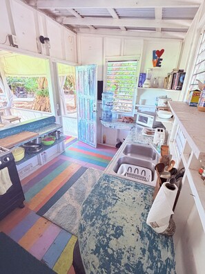 A kitchen with a colorful striped floor, a sink, a microwave, and a water dispenser. - Very popular industrial decor, meets beach luxury.  Close to beach! (San Pedro)