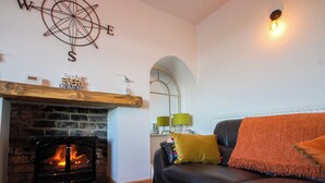 Un salon chaleureux avec une cheminée, un canapé en cuir et une boussole fixée au mur.