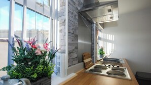 Une cuisine moderne avec un plan de travail en bois, une cuisinière intégrée et une grande fenêtre donnant sur l’extérieur.