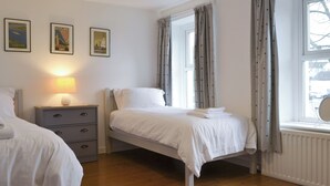 A bedroom with a bed, bedside table, lamp, and curtains.