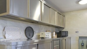 A stainless steel kitchen with a microwave, toaster, and a polka-dotted cutting board.