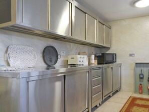 A stainless steel kitchen with a microwave, toaster, and a polka-dotted cutting board.