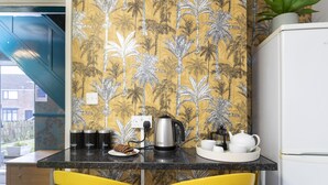 A kitchen with a tropical wallpaper, a coffee maker, and yellow chairs. - HC Property - Taylor Avenue (Durham)