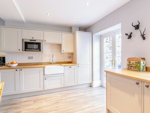 A modern kitchen with white cabinets, a microwave, and a wooden countertop.