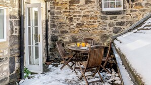 A stone building with a small outdoor seating area, a door, and a window. - 3 bedroom accommodation in Rothbury (Rothbury)