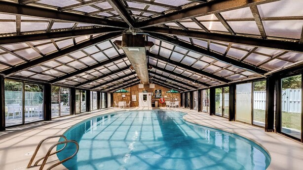 An indoor swimming pool with a glass ceiling, clear windows, and a lifeguard chair.