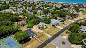 An aerial view of a residential area with houses, a tennis court, and a road.