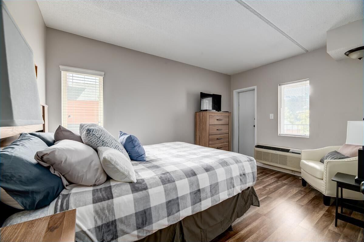 A bedroom with a bed, dresser, chair, and a window.