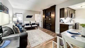 Una sala de estar moderna con sofá, sillones, chimenea y comedor con mesa y sillas.