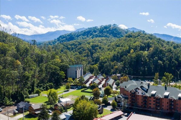 A hotel with a modern design, situated in a lush, green valley with mountains in the background.
