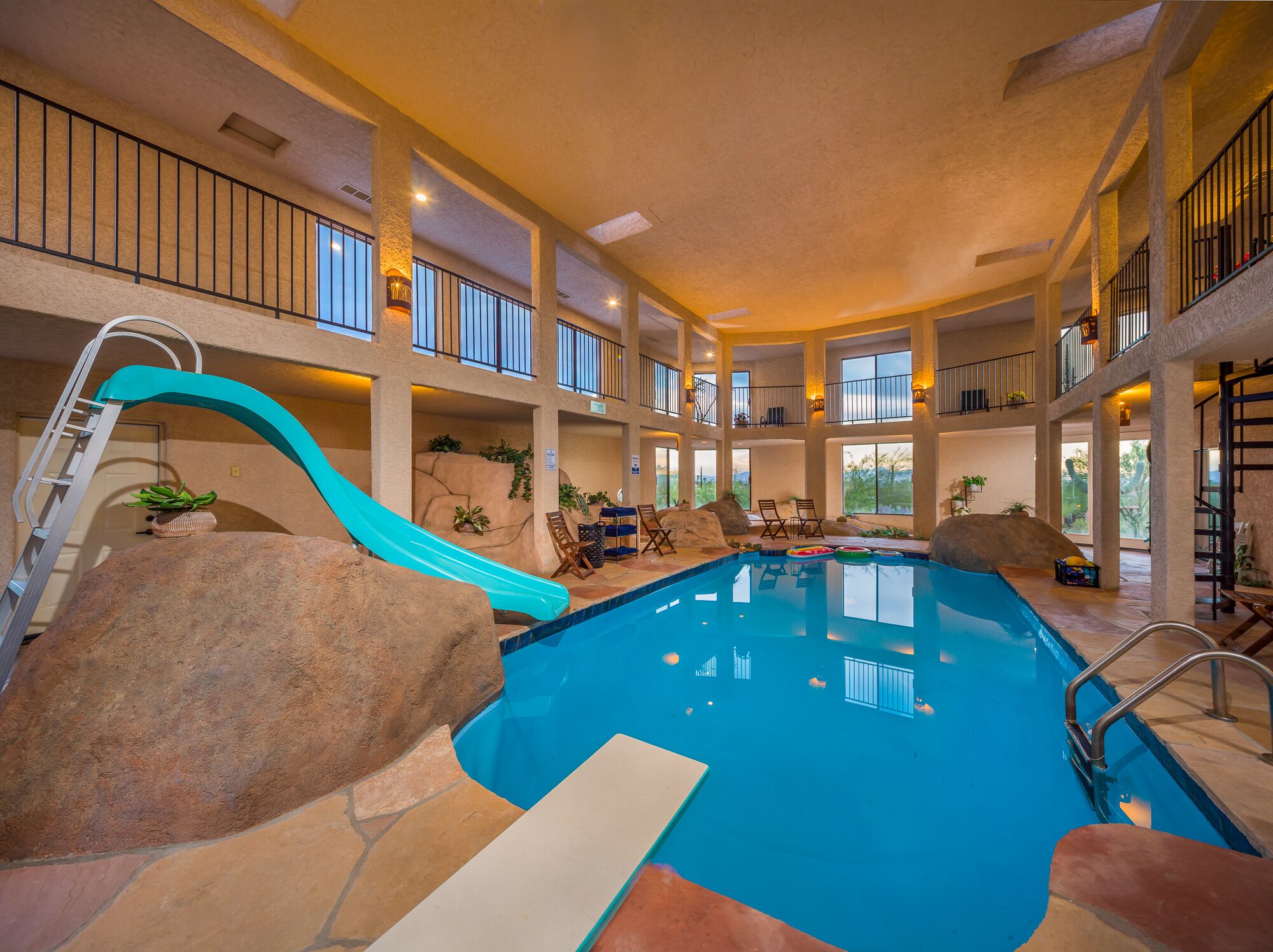 An indoor swimming pool with a slide, multiple balconies, and seating areas.