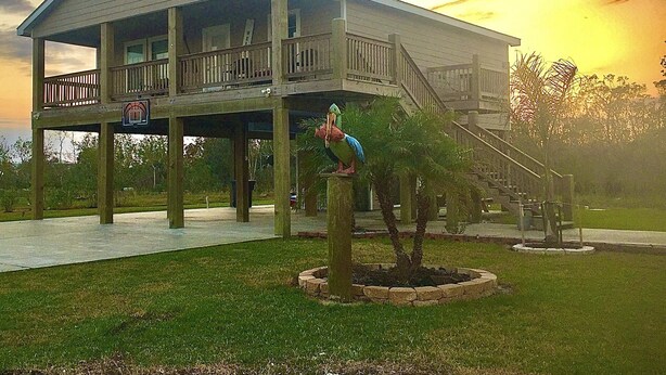 A two-story house with a balcony and a staircase leading to a deck. - 10% Discount- Hackberry Hideaway II Water View On Lake Calcasieu (Hackberry)
