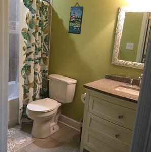 A bathroom with a toilet, sink, and shower curtain with a leaf pattern.