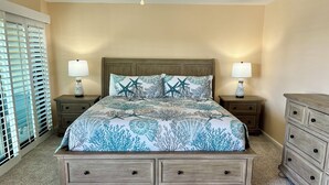 A bedroom with a bed, two nightstands, a dresser, and a window with blinds.