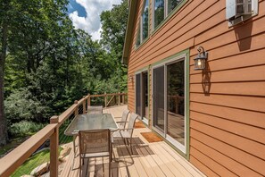 A wooden deck with a glass door leading to a covered patio area.