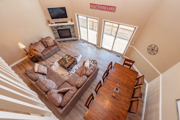 A spacious living room with a large sectional sofa, a wooden dining table, and a fireplace.