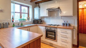 Une cuisine moderne avec des poutres en bois, un four encastré, un four à micro-ondes et un évier.