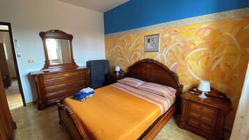 A bedroom with a bed, dresser, nightstand, and a chair.