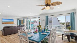 Un coin repas avec une table bleue, des chaises blanches et un ventilateur de plafond.