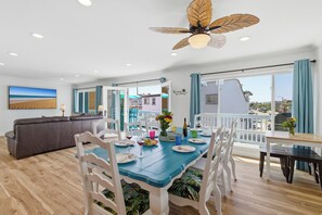 A dining area with a blue table, white chairs, and a ceiling fan.