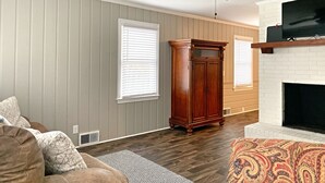 A living room with a ceiling fan, a fireplace, and a large TV mounted above it. - Quiet home in the Kernersville near Winston Salem, Greensboro, High Point (Kernersville)