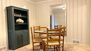 A dining area with a wooden table and chairs, a dark wooden cabinet with shelves, and a large mirror on the wall. - Quiet home in the Kernersville near Winston Salem, Greensboro, High Point (Kernersville)