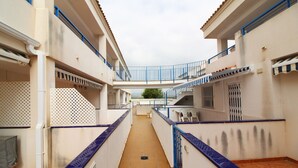 A narrow corridor with tiled flooring, white walls, and blue railings. - Global Vacacional: Apartment with pool in Corinto beach (Sagunto)