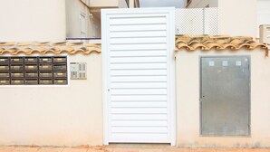 A white door with horizontal slats, a metal utility box, and a tiled roof. - Global Vacacional: Apartment with pool in Corinto beach (Sagunto)