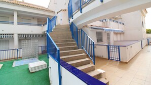 A multi-level building with a central staircase, multiple balconies, and a tiled floor. - Global Vacacional: Apartment with pool in Corinto beach (Sagunto)
