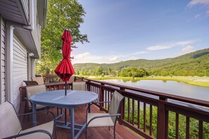 Una terraza con mesa y sillas, con vista a un lago y colinas.