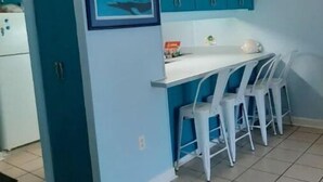 Una cocina con armarios color turquesa, encimera blanca y un cuadro con una imagen de tiburón.