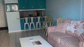 Una sala de estar con un sofá a rayas, una mesa de centro de madera y un comedor con sillas y una mesa.