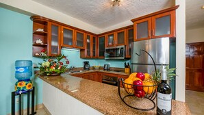 Eine Küche mit Holzausstattung, einem Edelstahlkühlschrank, einer Mikrowelle und einer Arbeitsplatte aus Granit.