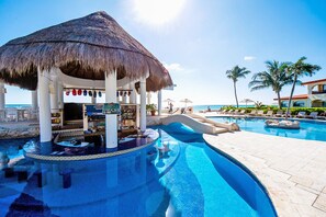 A pool area with a bar, lounge chairs, and a thatched-roof structure.