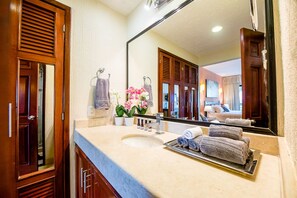 A bathroom with a large mirror, wooden doors, a sink, and towels.