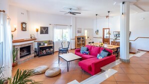 Ein geräumiges Wohnzimmer mit Kamin, einem roten Sofa und einem Essbereich mit Holztisch und Stühlen.