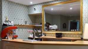 Uma área de bar com uma máquina de café, um espelho e uma garrafa de Bacardi.
