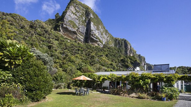 A building with a garden, outdoor seating, and a mountain backdrop. - Cliffscapes Punakaiki (Punakaiki)