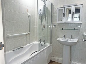 A modern bathroom with a glass-enclosed shower, a white bathtub, and a pedestal sink.