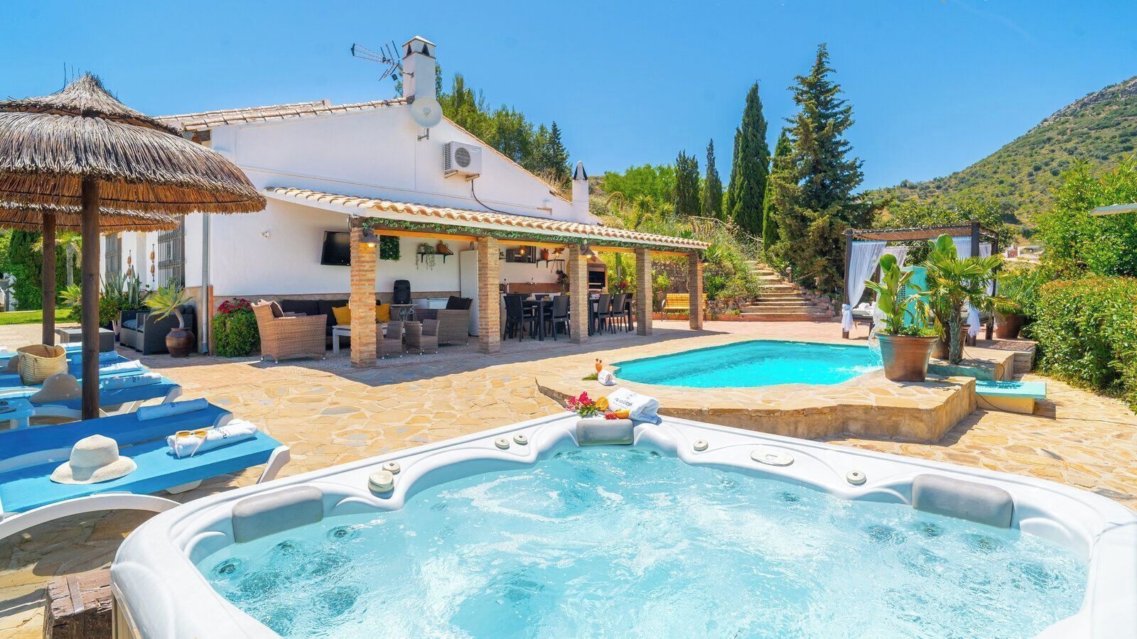 A pool area with hot tubs, lounge chairs, and a covered patio.