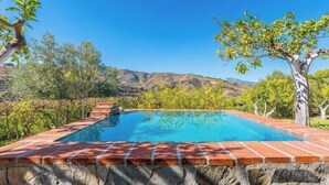 A rectangular swimming pool with a brick edge, surrounded by greenery and hills in the background. - Casa Ami Guaro by Ruralidays (Málaga)