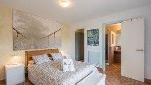 A bedroom with a large bed, a headboard, two bedside tables, a nightstand, a wall-mounted artwork, and a poster. - Casa Ami Guaro by Ruralidays (Málaga)