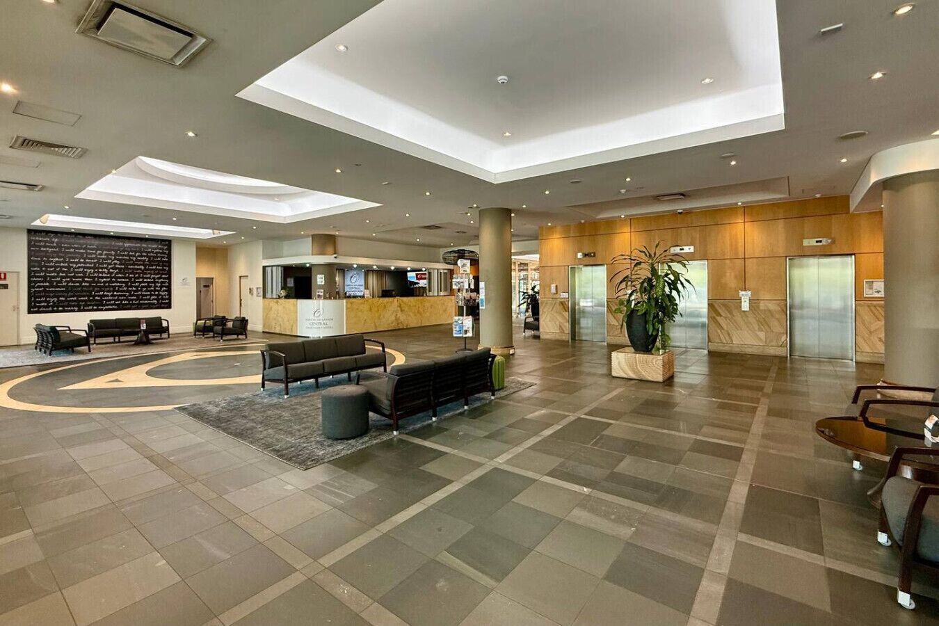 A spacious lobby with a reception desk, seating area, and a large plant.
