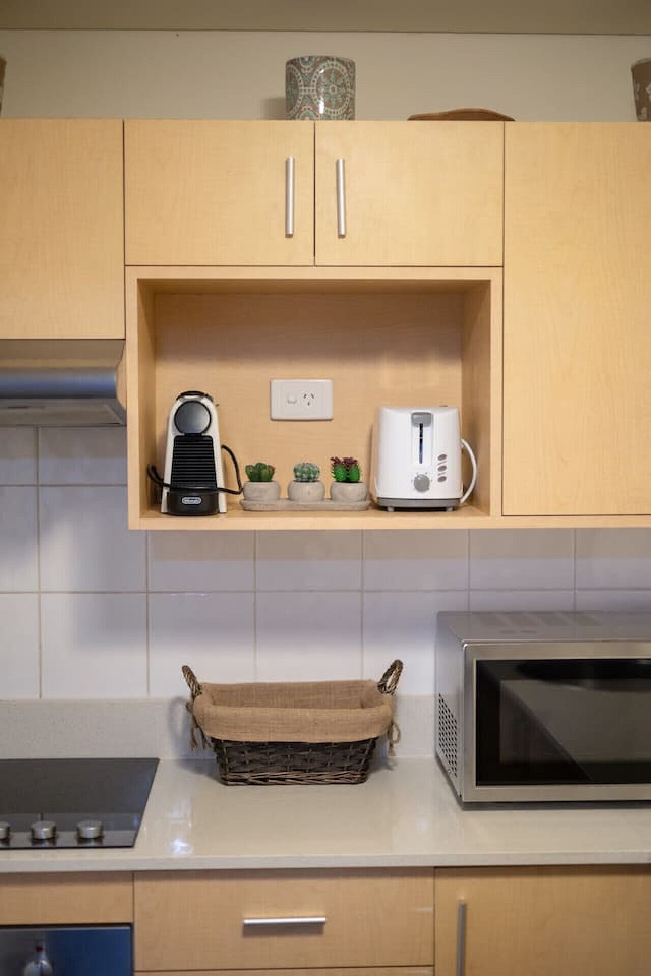 A kitchen with wooden cabinets, a microwave, a toaster, and a basket on the counter.