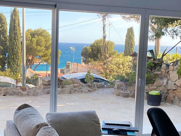 A room with a view of the sea, a stone wall, and a chair.