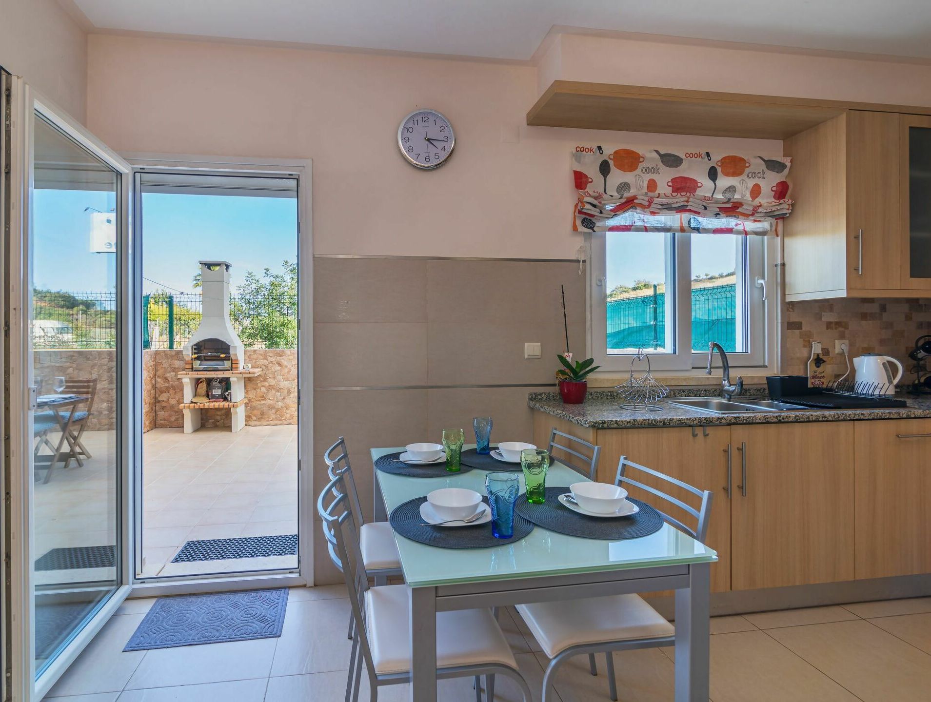Una cocina moderna con comedor, un reloj en la pared y vistas al exterior.