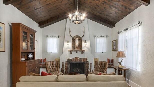 A cozy living room with a fireplace, wooden ceiling, and a chandelier. - Emmie's | Great Location (Fredericksburg)