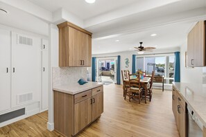 Une cuisine moderne avec des meubles en bois, un plan de travail en marbre et un coin repas comprenant une table et des chaises.