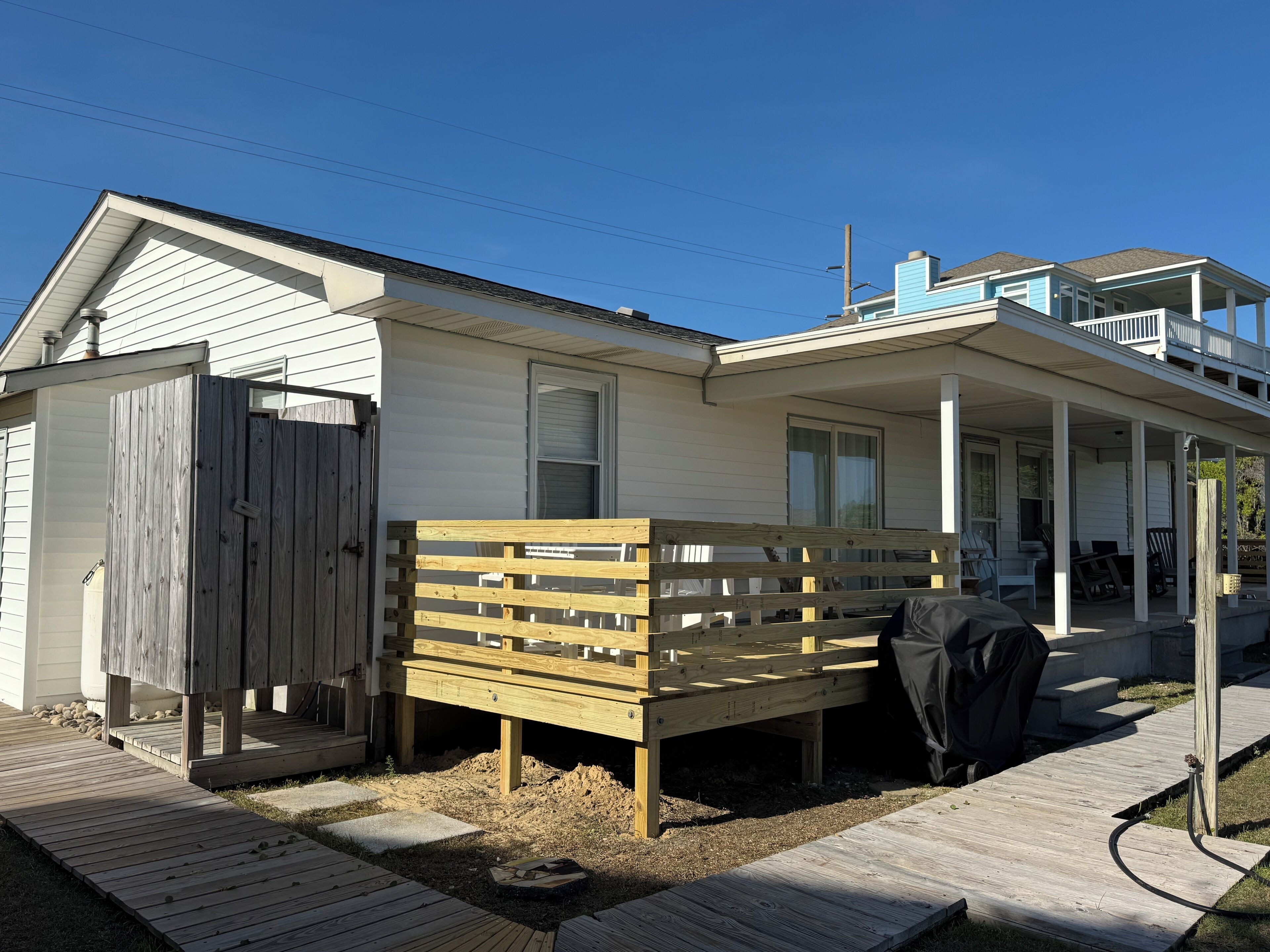 A two-story house with a covered porch, a fenced backyard, and a wooden deck.